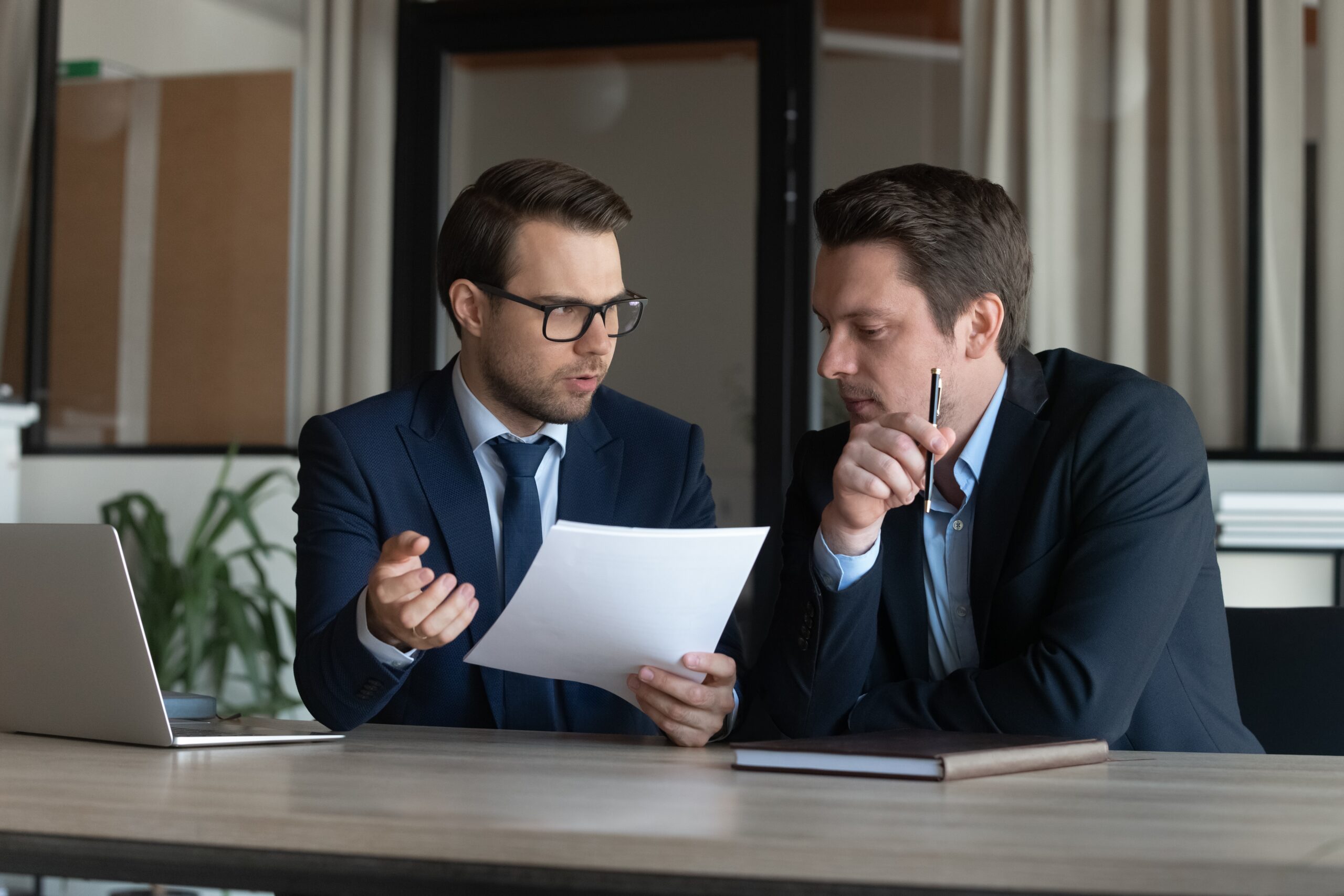 A consultant and another professional sitting at a table discussing how to achieve SOC 2 compliance.