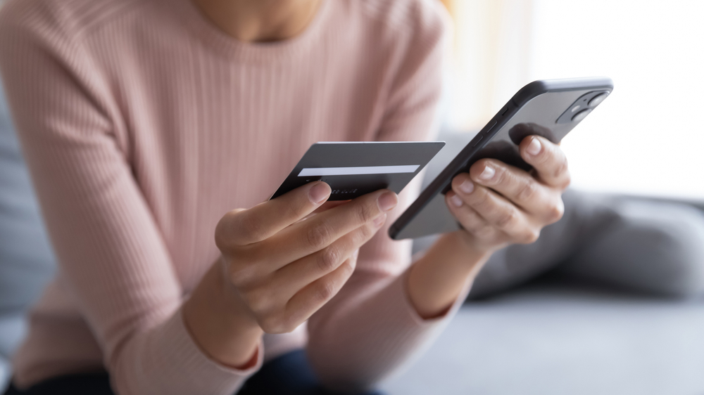 lady is paying for something online via her mobile phone with her credit card, trusting PCI-DSS compliance