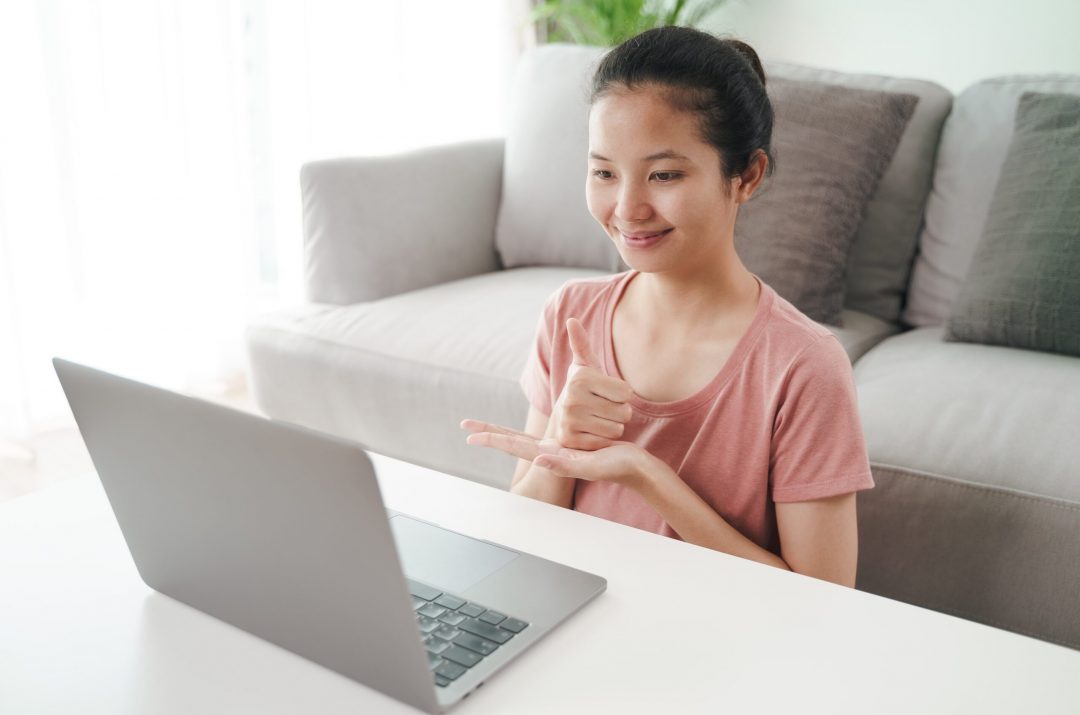 audio-description-services-allowing-young-asian-woman-deaf-disabled-use-laptop-computer-online-video-conference-call-learning-communicating-sign-language young girl who is deaf is able to use laptop after audio description services