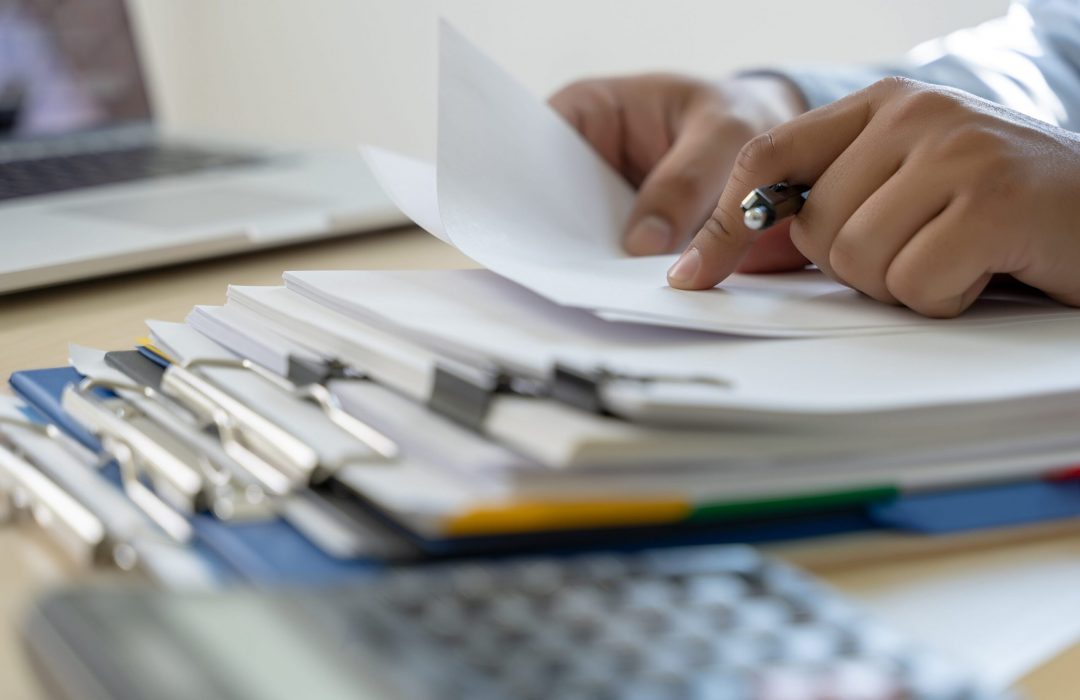 person's hands holding papers on top of policies and procedures