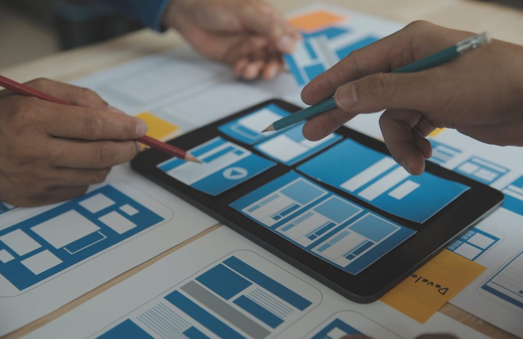 close-up-ux-developer-ui-designer-brainstorming-about-mobile-app-interface-wireframe-design-table-with-customer-breif-color-code-modern-officecreative-digital-development-agency-min people working on tablet focused on user experience