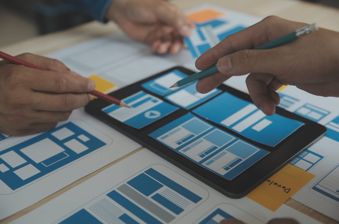 close-up-ux-developer-ui-designer-brainstorming-about-mobile-app-interface-wireframe-design-table-with-customer-breif-color-code-modern-officecreative-digital-development-agency-min people working on tablet focused on user experience