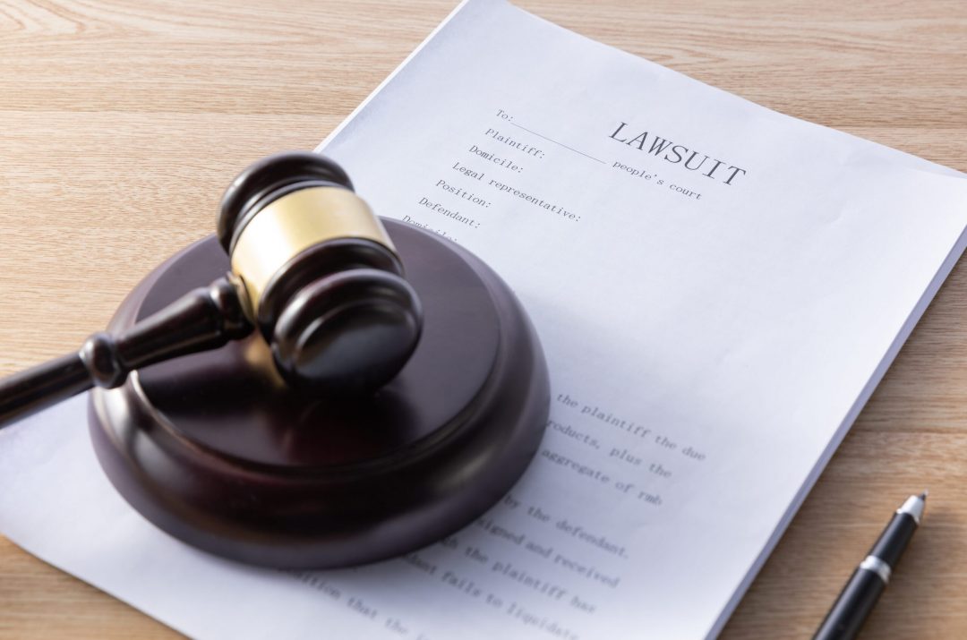high-angle-shot-gavel-lawsuit-papers-wooden-surface-min gavel and lawsuit paperwork