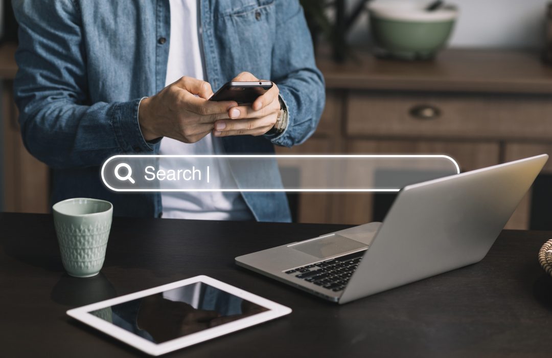 homepage-concept-with-search-bar-min person using smart phone to search the internet using seo