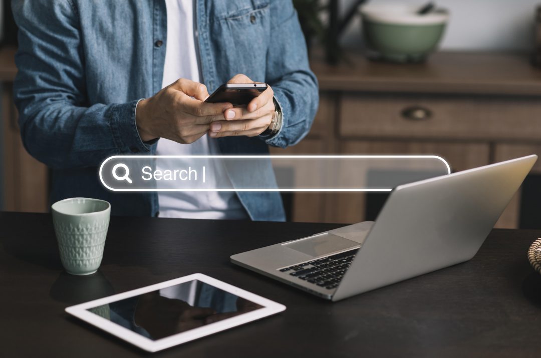 homepage-concept-with-search-bar-min person using smart phone to search the internet using seo