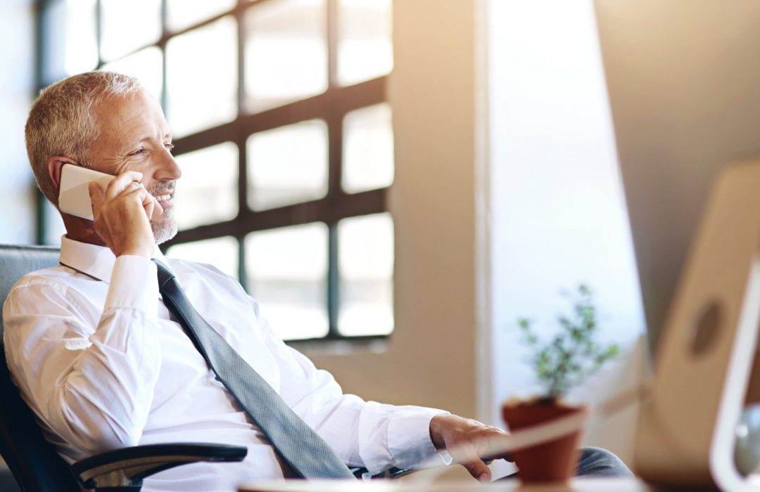 businessman on the phone giving client support in an office with a window on the side