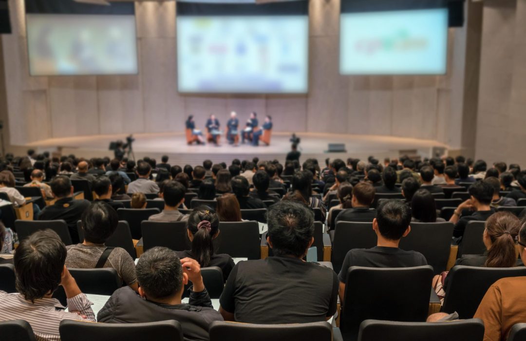 speaking to a large audience in an auditorium