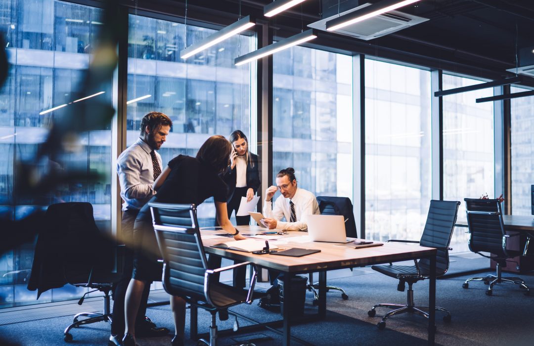 a group of working professionals meeting at a table in an office