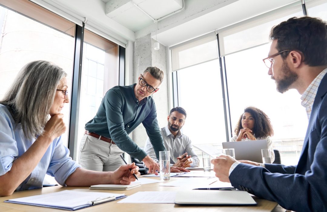 men and women professionals conversing at a long business table