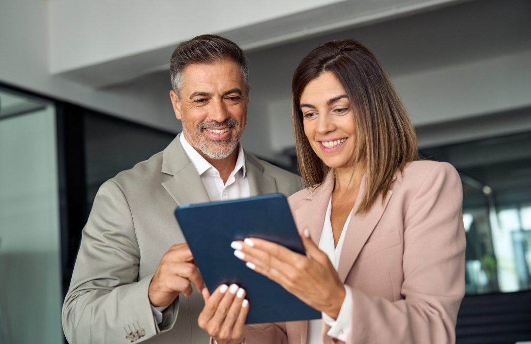 businessman and business woman looking at a tablet smiling