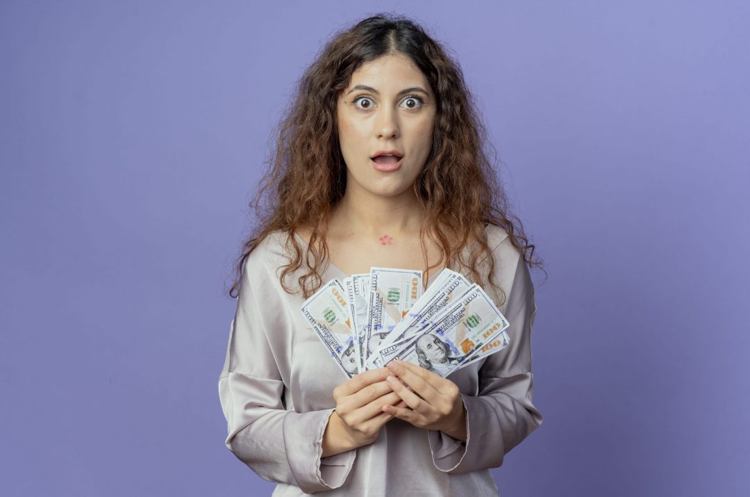 surprised girl saving money standing in front of purple background